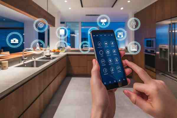 A person holding a smartphone to control smart features in a well-lit modern kitchen.